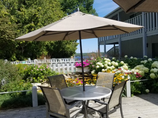 Pool deck with table surrounded by a flower garden